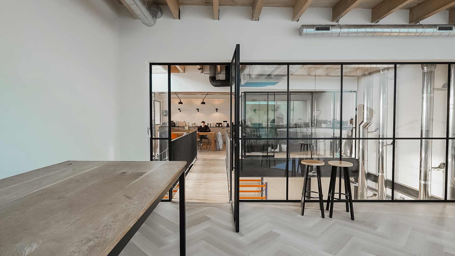 Openstaande scharnierdeur bij een glazen kantoorwand.